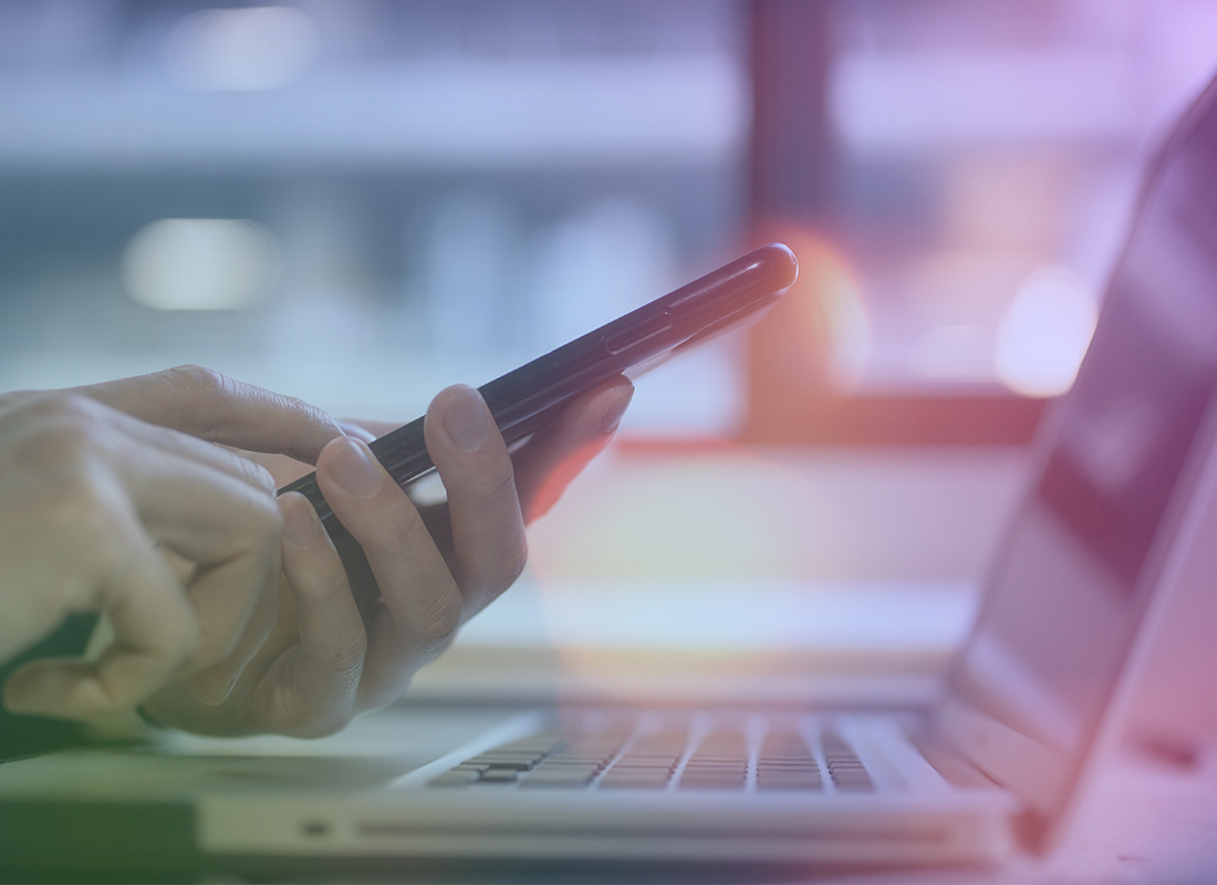 Person at desk using mobile phone and laptop